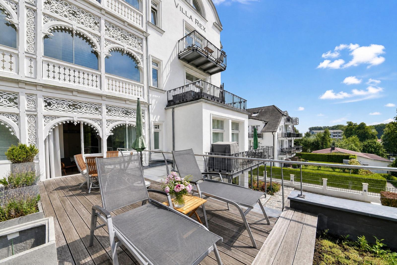 Terrasse mit Liegestühlen und Blick auf Villa Rex und Garten.