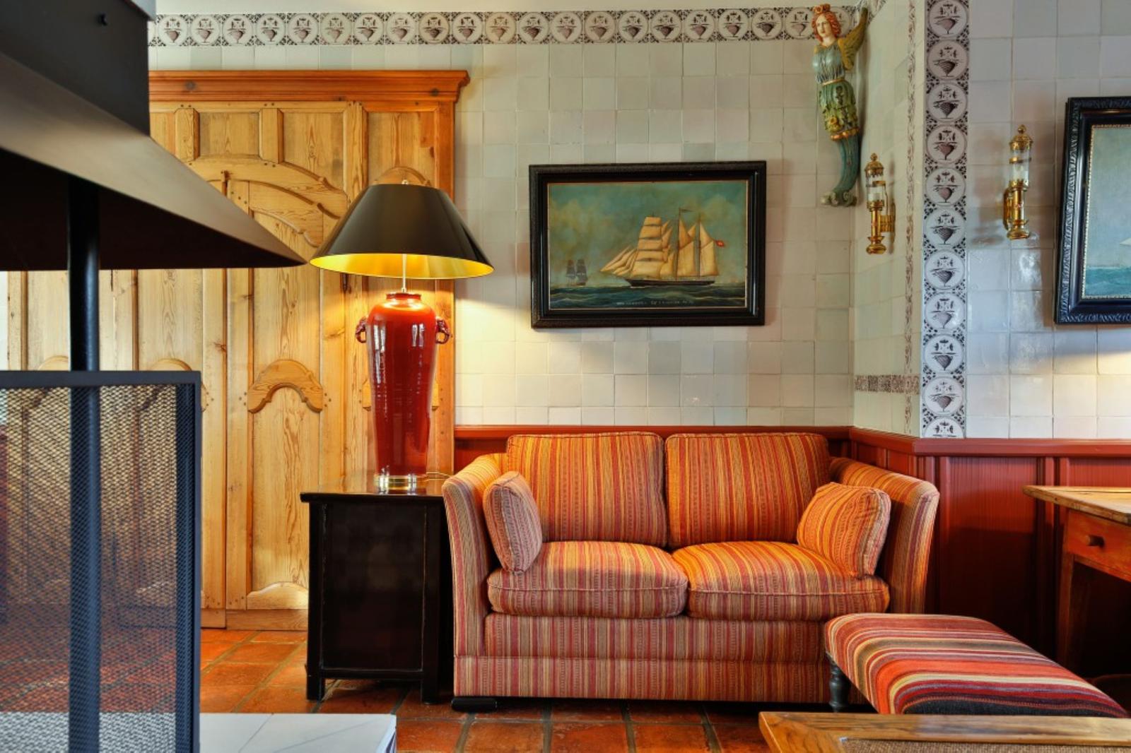 Ein Sofa mit Streifenmuster steht vor einer Wand mit Fliesen und einem Bild.