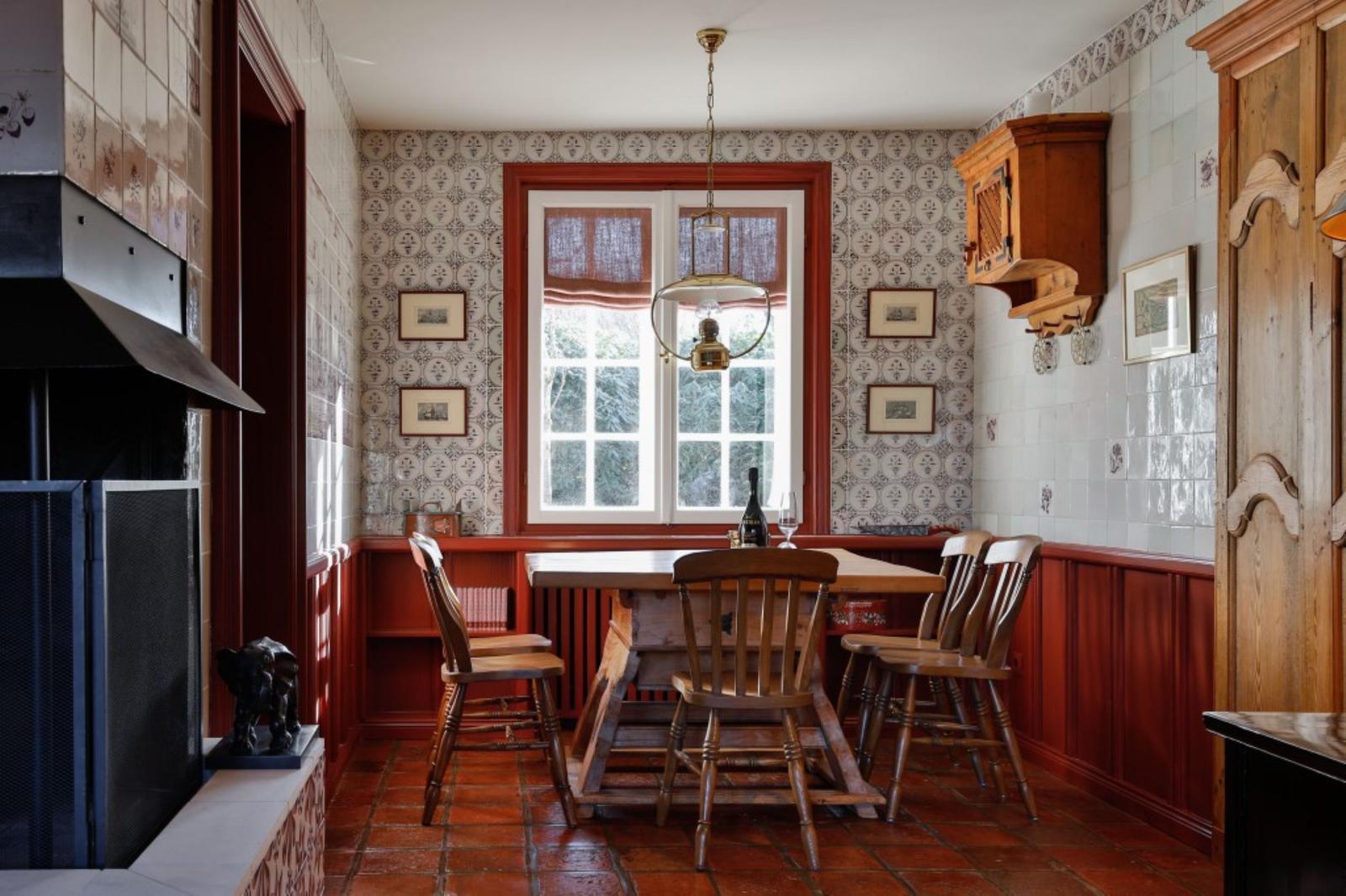 Esszimmer mit Holztisch, Stühlen, Fenster und Kachelwand.
