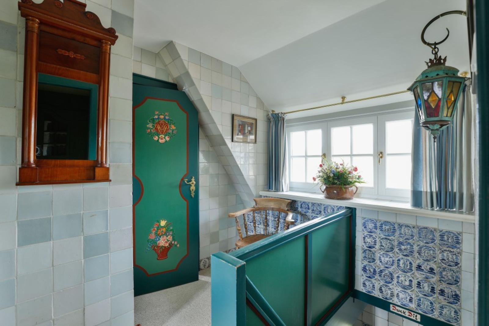 Treppe mit grüner Treppe, Tür mit Blumenmotiv und Fenster mit Blumenkasten.
