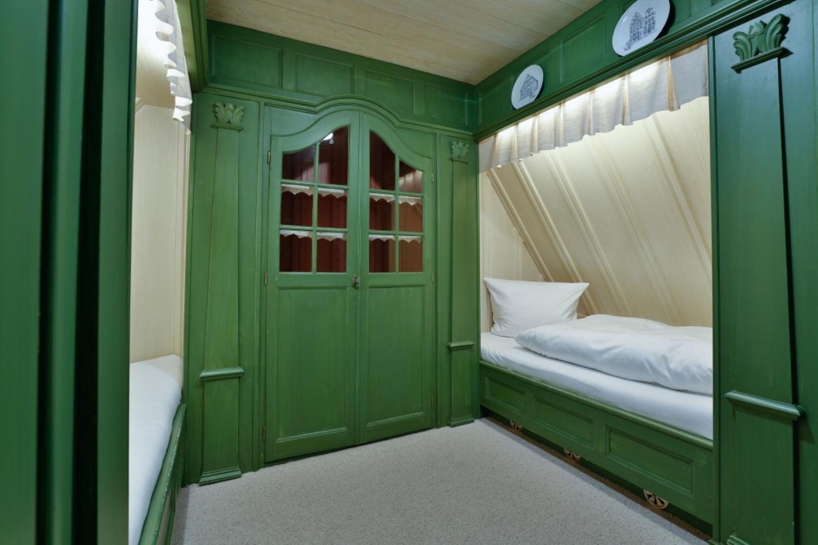 Zimmer mit grünem Schrank und Bett unter Dachschräge.