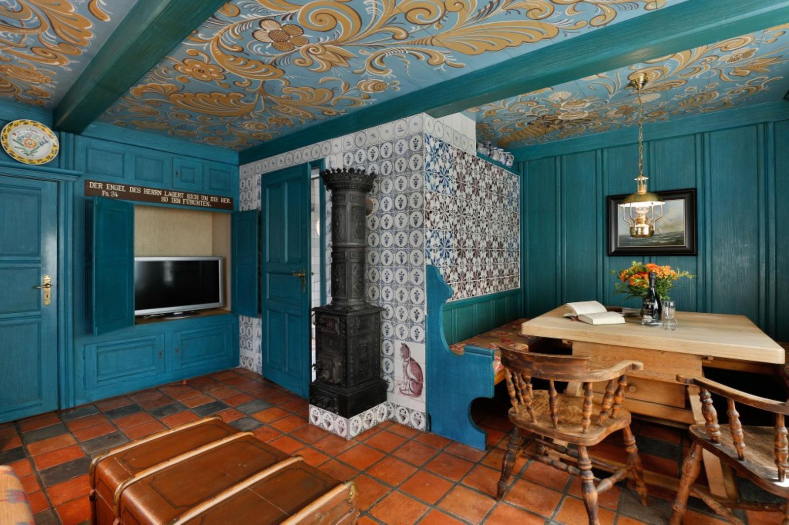 Raum mit blauen Wänden, bemaltem Decken und Holztisch mit Stühlen.