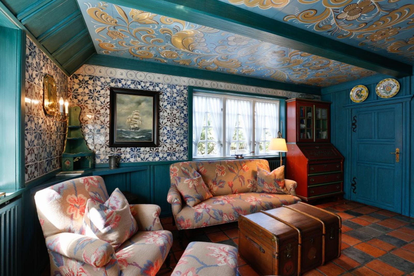 Raum mit blauem Holz, floralen Tapeten und einem Sofa mit Kissen.