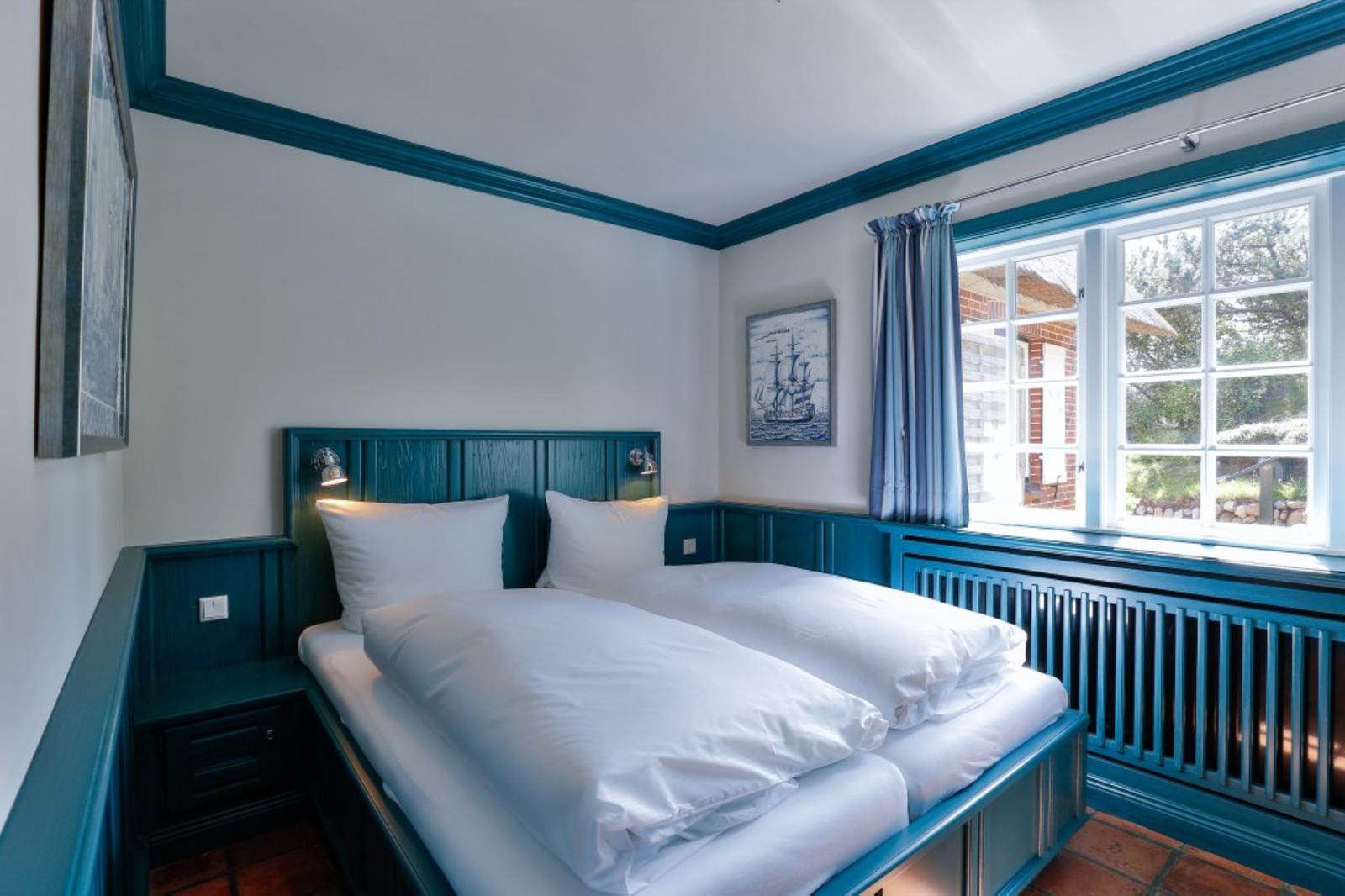 Schlafzimmer mit Bett, Fenster und Wanddekoration.