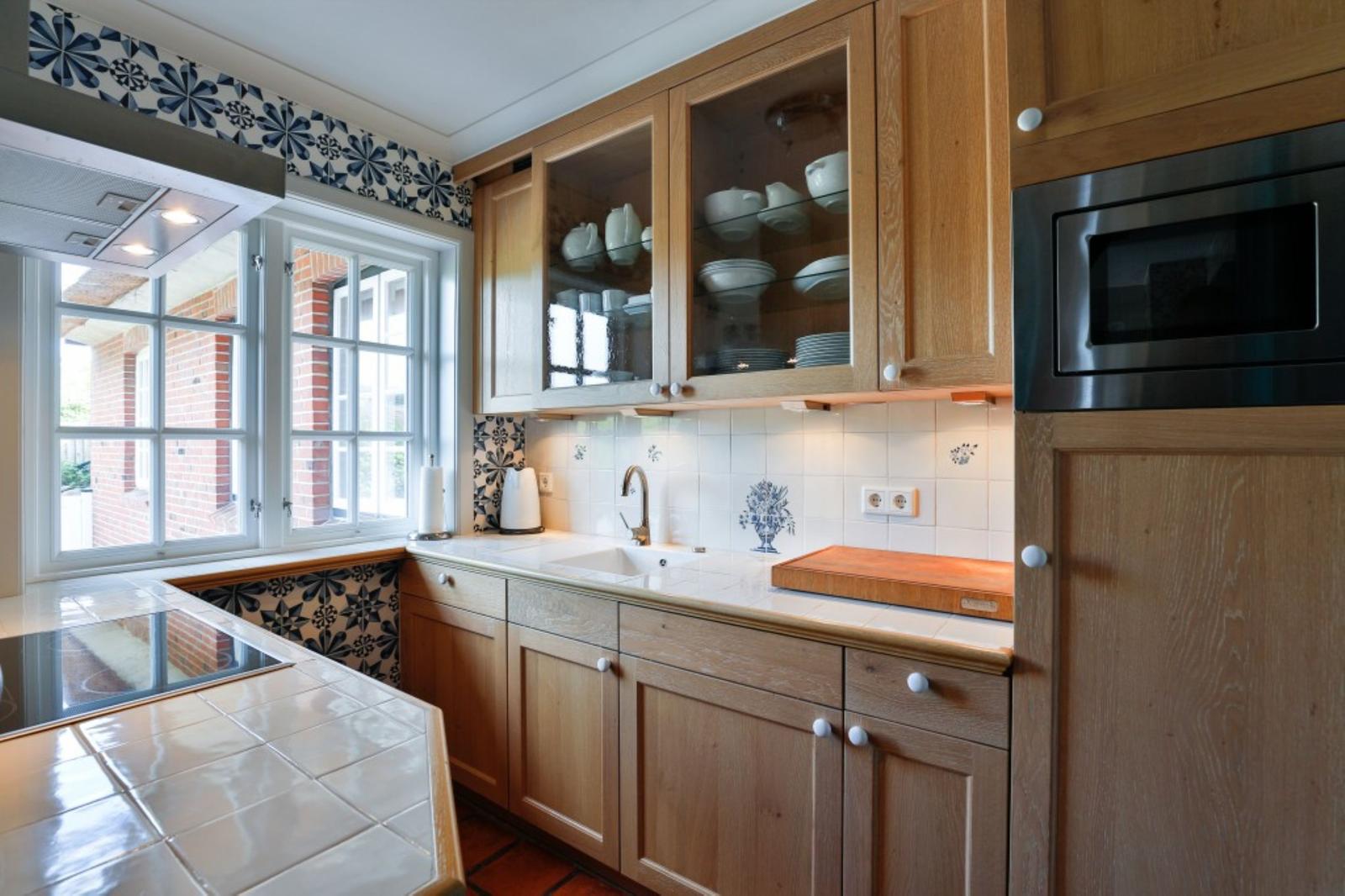 Küche mit Holzschränken, Fenster und Backsteinmauer im Hintergrund