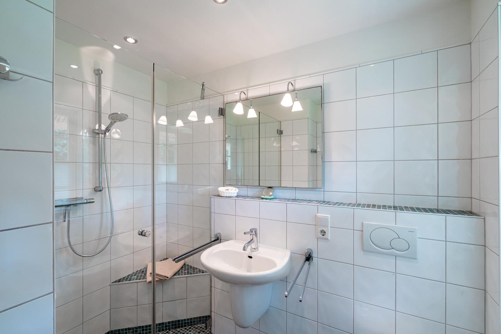 Badezimmer mit Dusche, Waschbecken und Spiegel