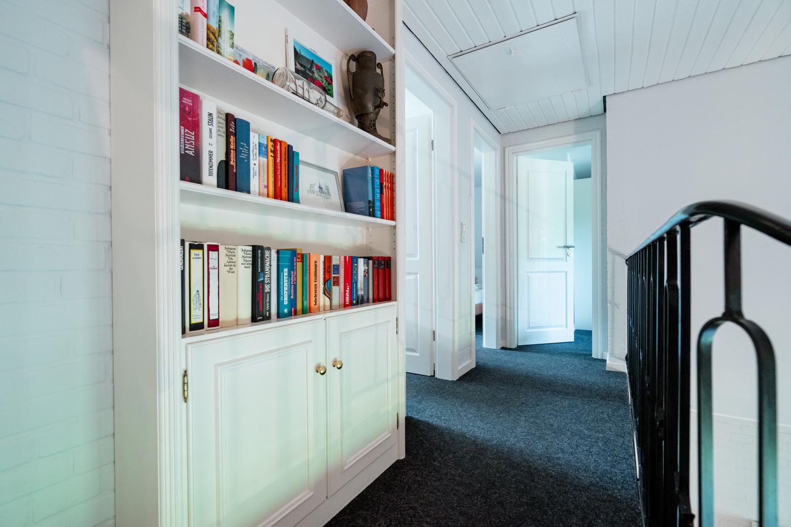Flur mit Bücherregal, Treppenhaus und Türen zu Räumen