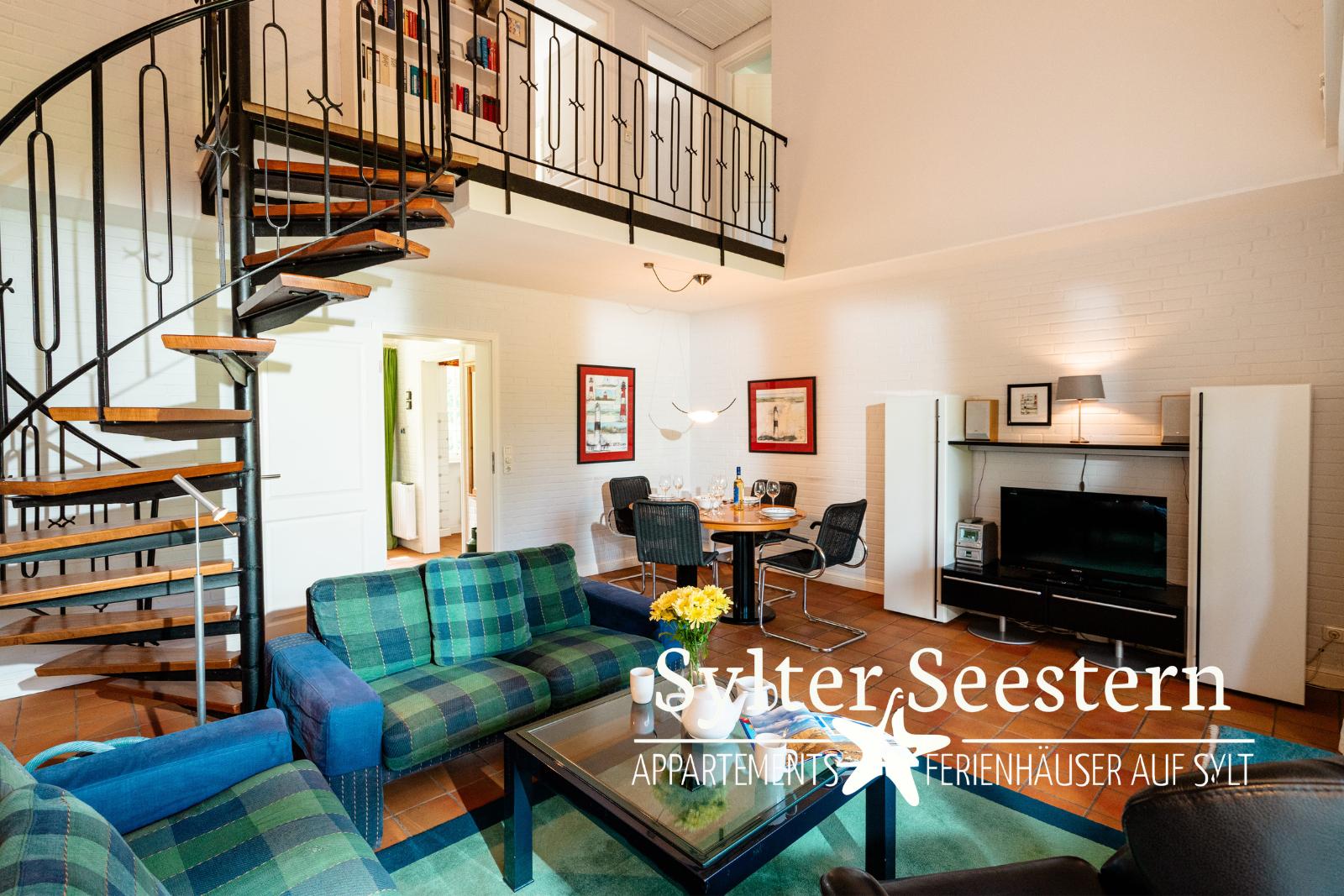 Wohnung mit Spiral-Leiter, Sofa, Esstisch und Fernseher.