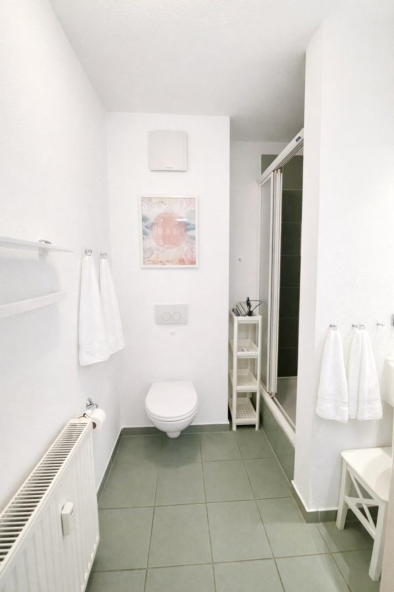 Badezimmer mit Toilette, Dusche und Handtuchhalterungen.