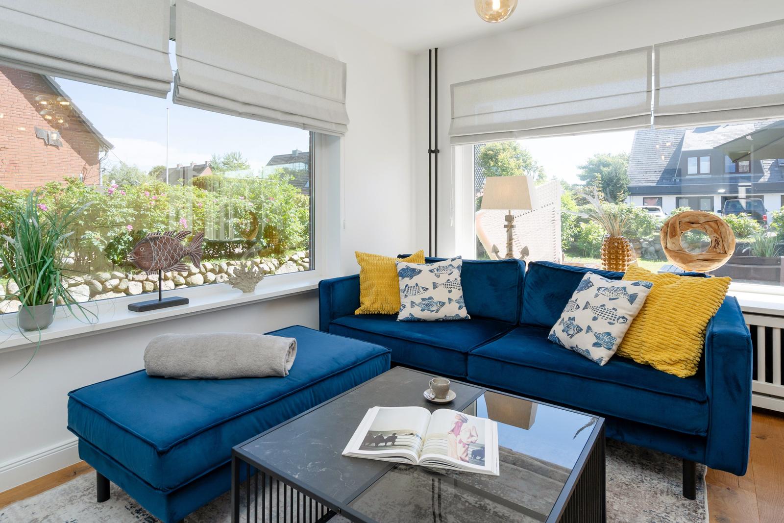 Blauer Sofa mit Kissen und Couchtisch im Wohnzimmer mit Fenstern.