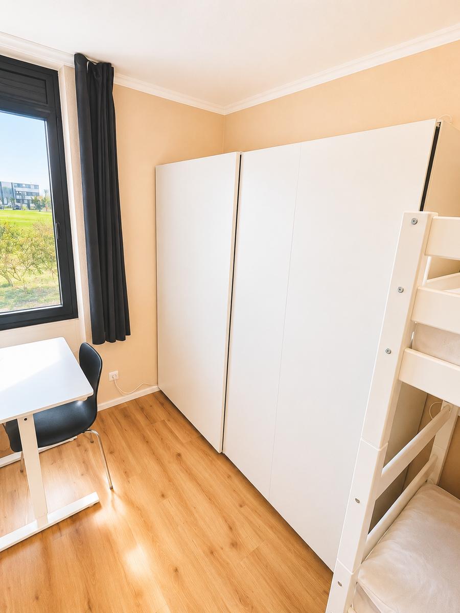Großer Schrank mit Ablagefläche für Gepäckstücke obendrauf im kleinen Zimmer