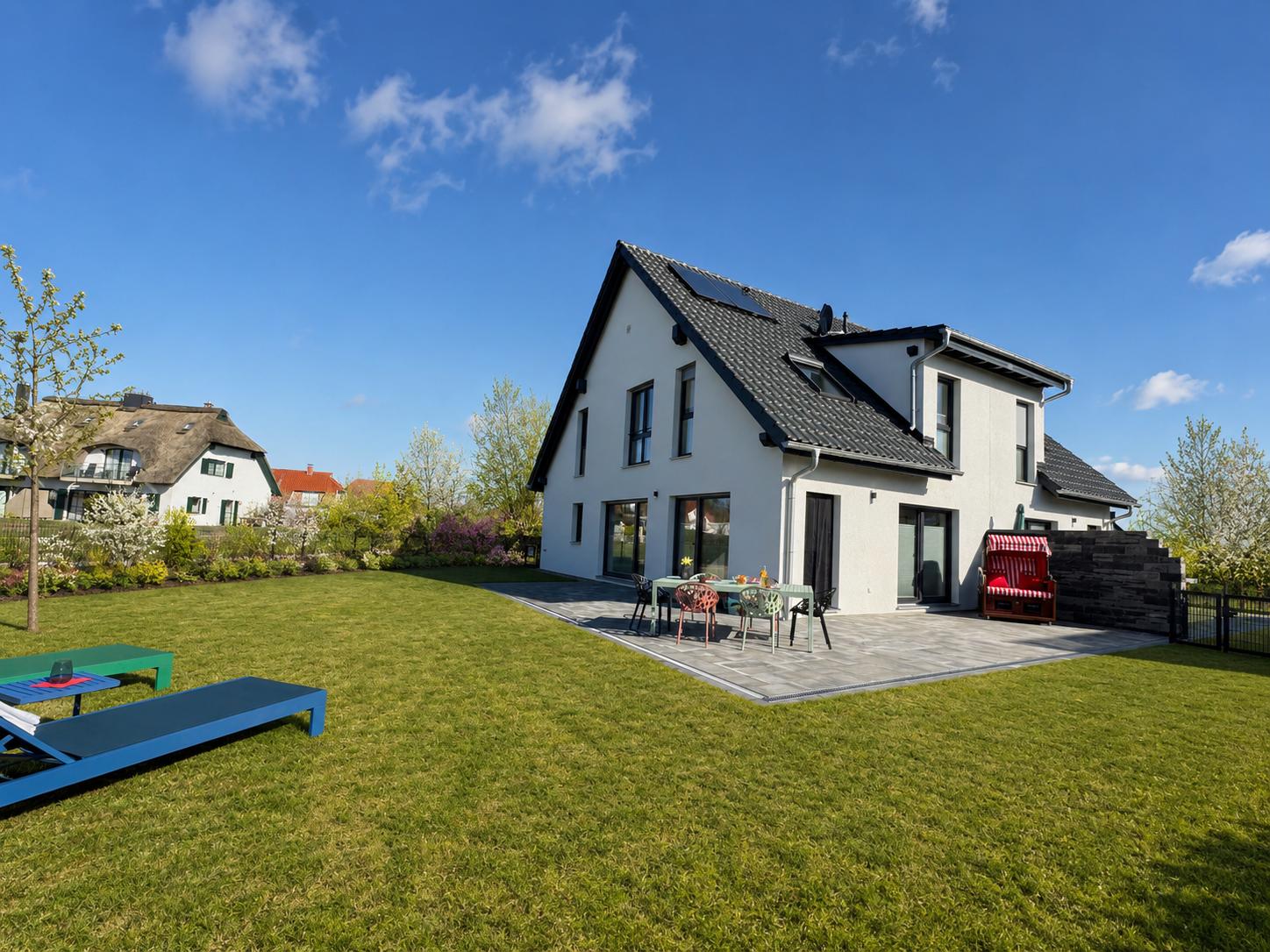 Modernes Haus mit großem Garten und Terrasse mit Gartenmöbeln.