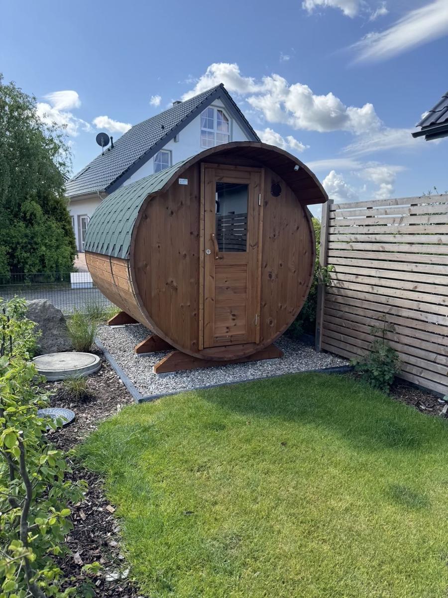 Holzsauna im Garten mit Tür und grünem Dach