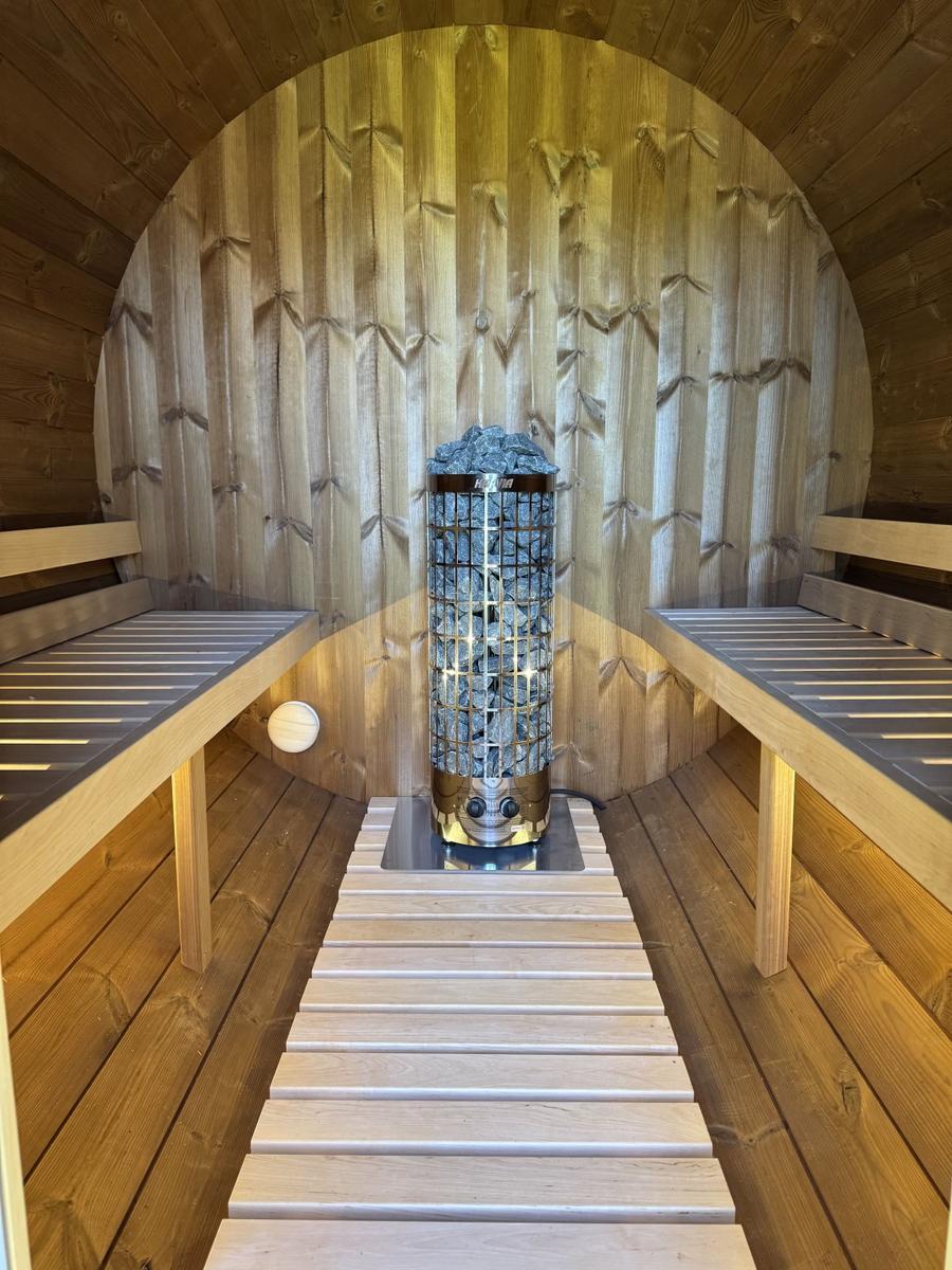 Sauna mit Holzwand, Steinkamin und zwei Sitzbänken