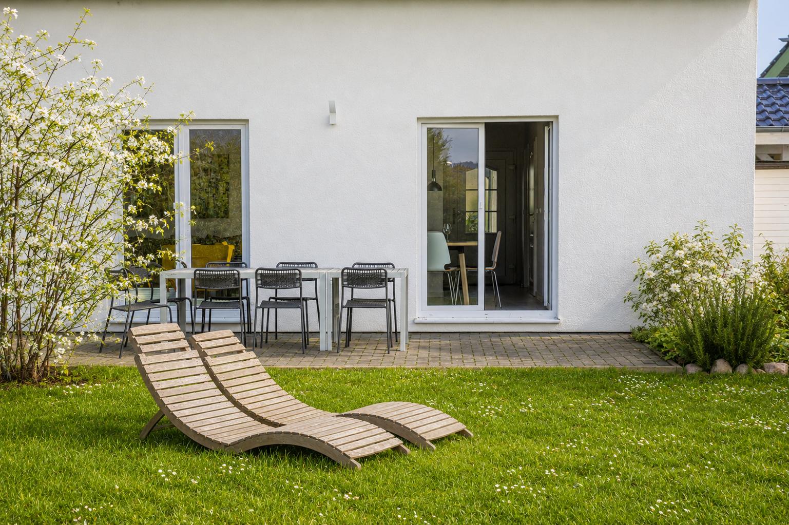 Hinterhof mit Liegestühlen, Tisch und Stühlen sowie Blick in die Küche.