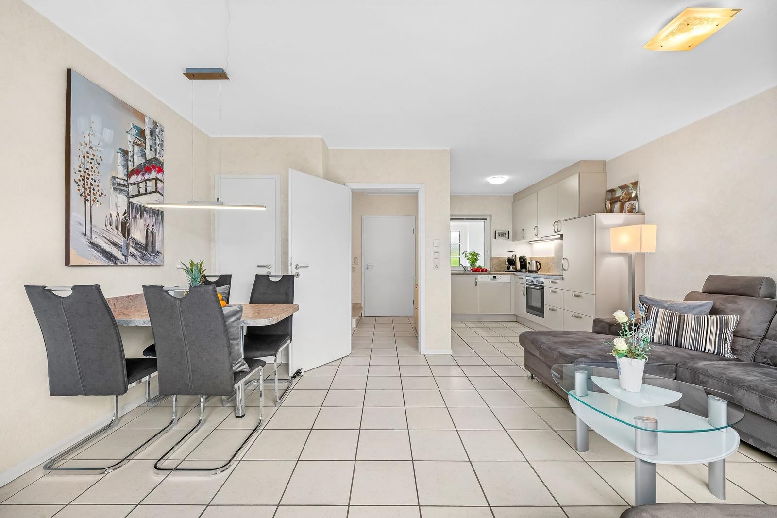 Wohnung mit Essbereich, Küche und Wohnzimmer mit Sofa und Glas-Tisch.