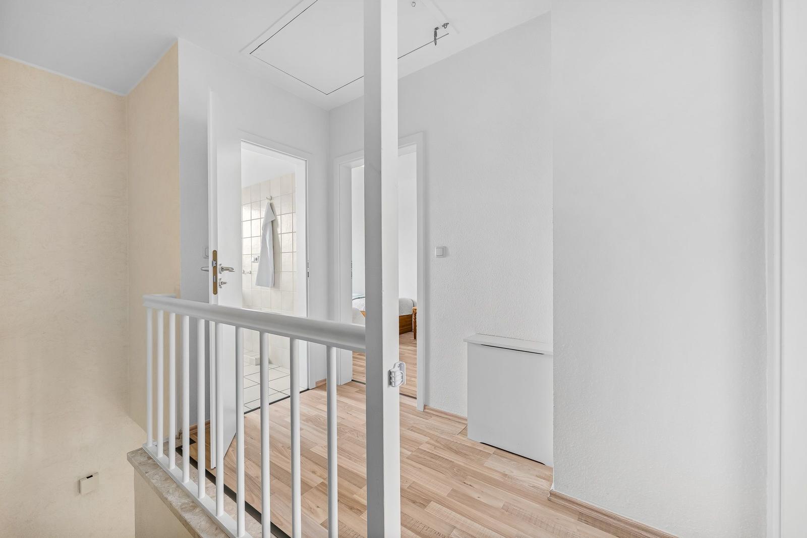 Haus mit Holzboden, weißen Wänden und Blick in Bad und Schlafzimmer.