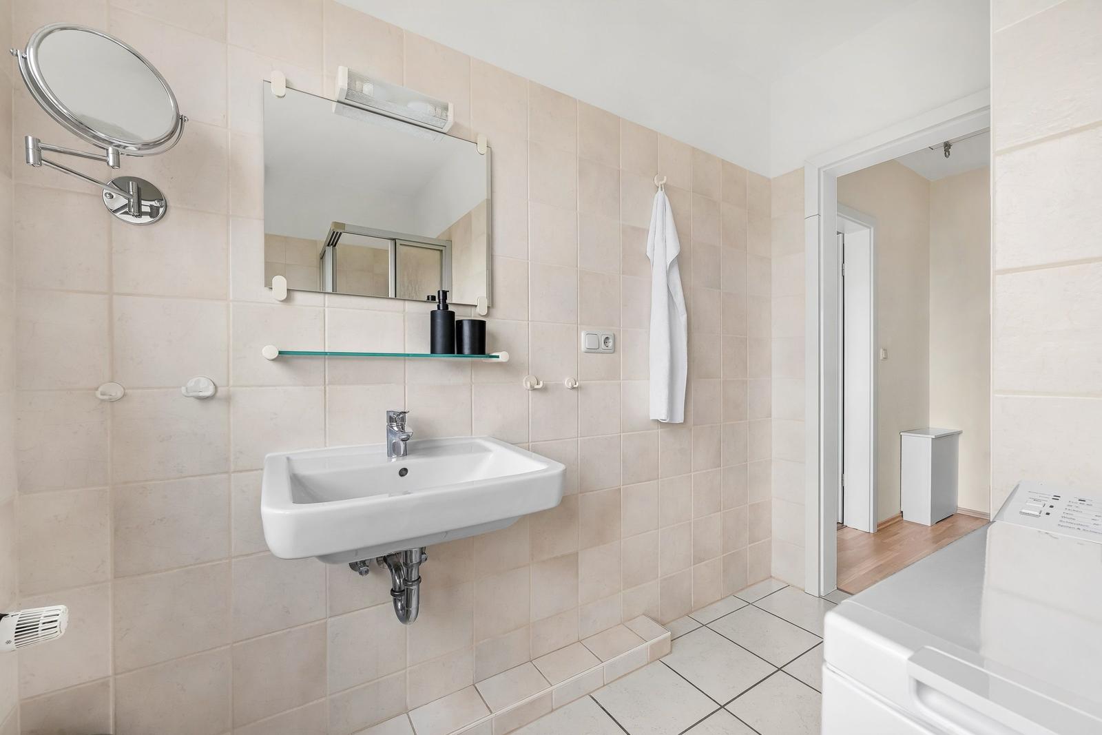 Badezimmer mit Waschbecken, Spiegel und Waschmaschine