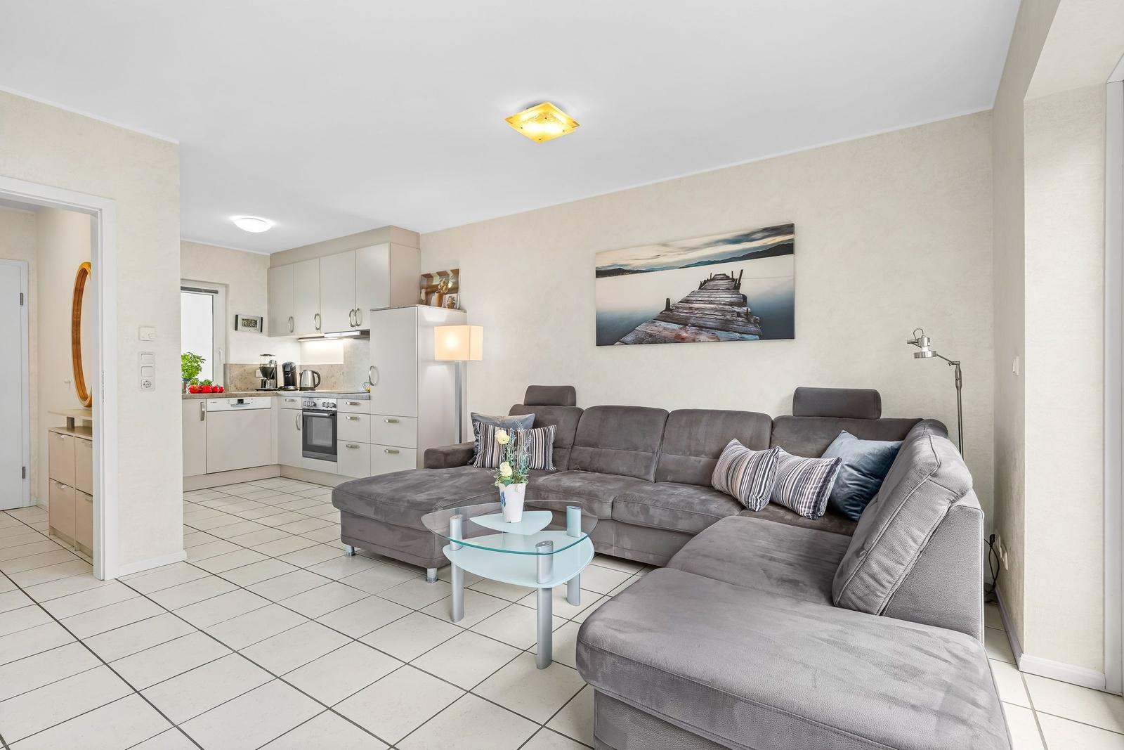 Wohnzimmer mit Sofa, Couchtisch und Küchenbereich im Hintergrund.