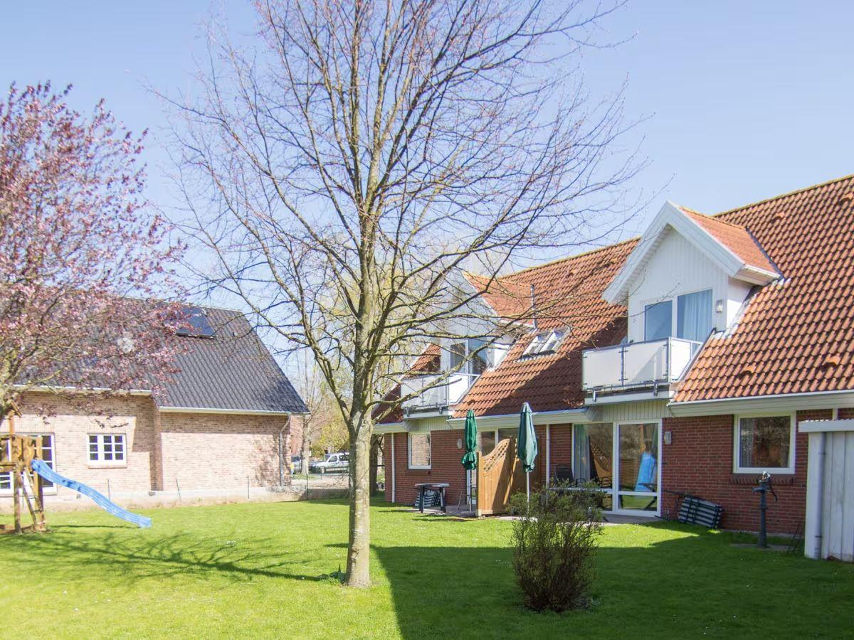 Haus mit Garten, Baum und Spielplatz. Terrasse mit Sonnenschirm.