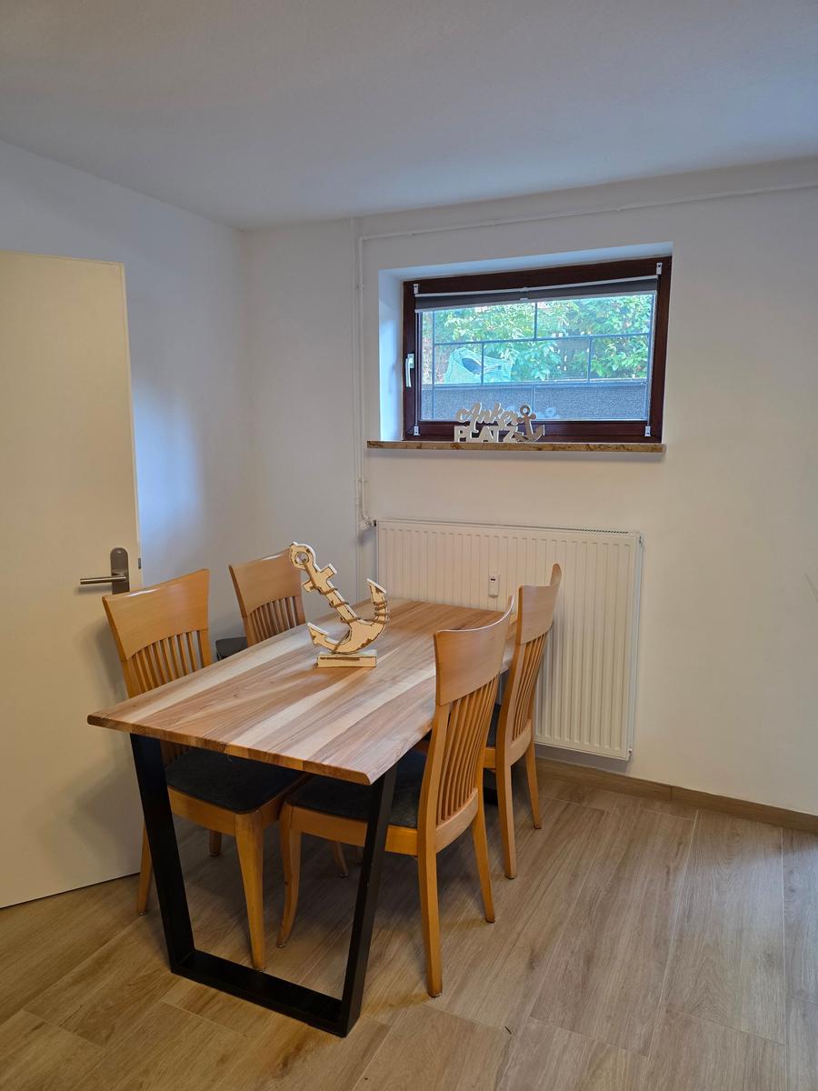 Esszimmer mit Holztisch, vier Stühlen und Fenster mit Blick auf Grün.
