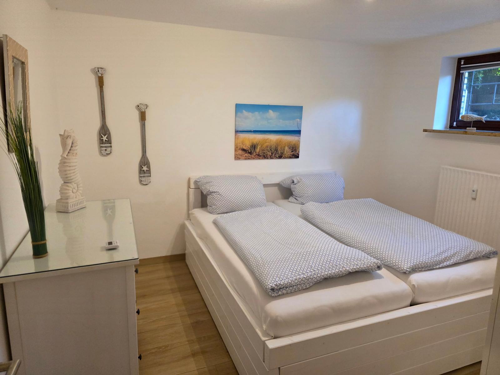 Schlafzimmer mit Doppelbett, Wanddekoration und Fenster.