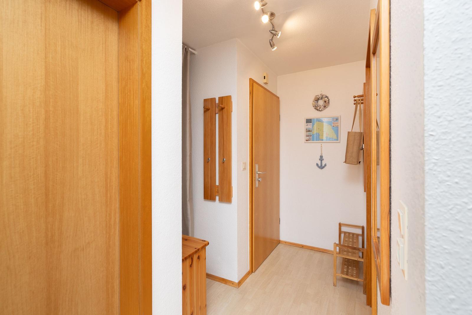 Flur mit Holztüren, Wanddekoration und einem kleinen Holzstuhl.