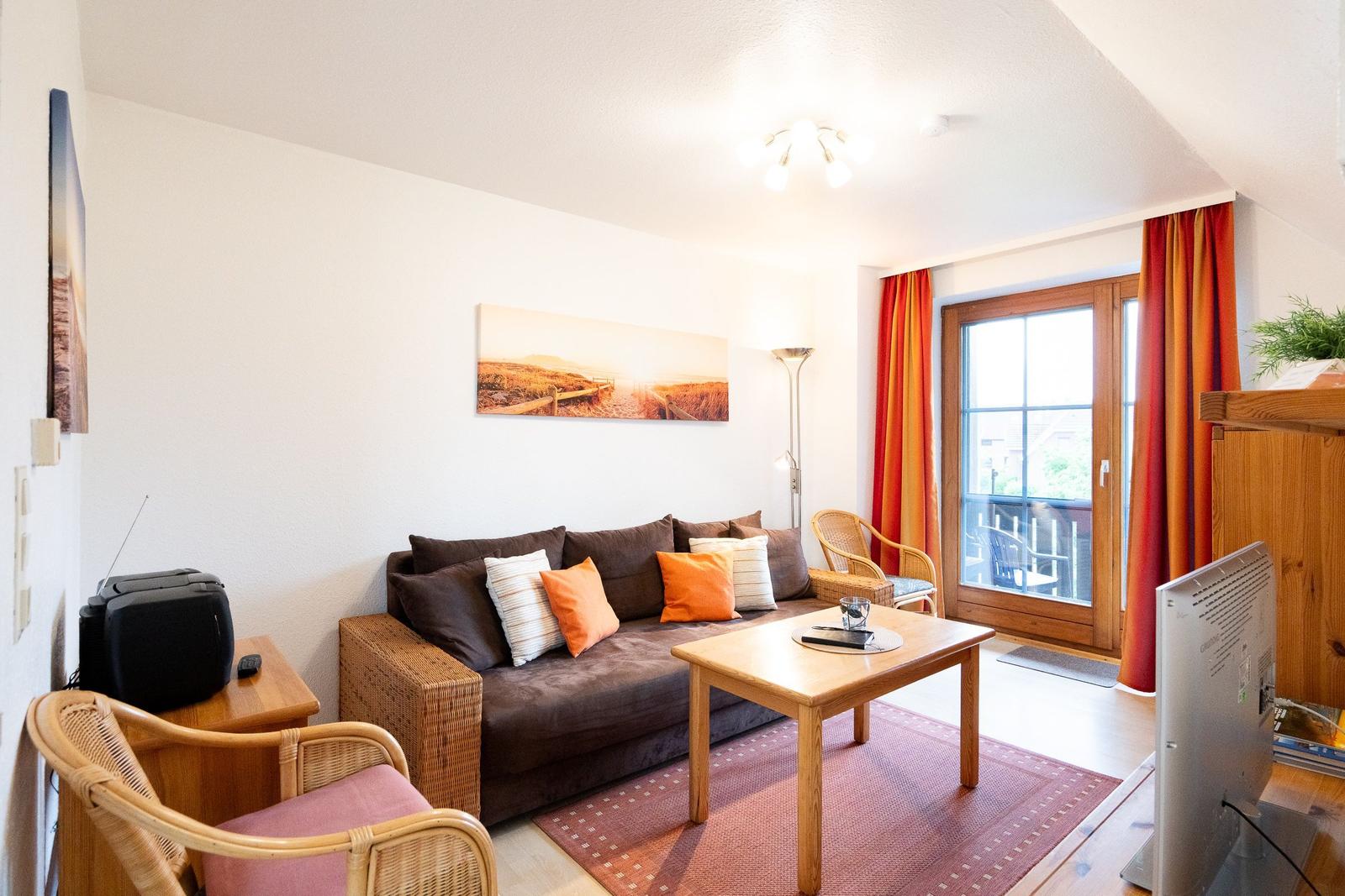 Wohnzimmer mit Sofa, Tisch, Stühlen und Fenster mit Blick.