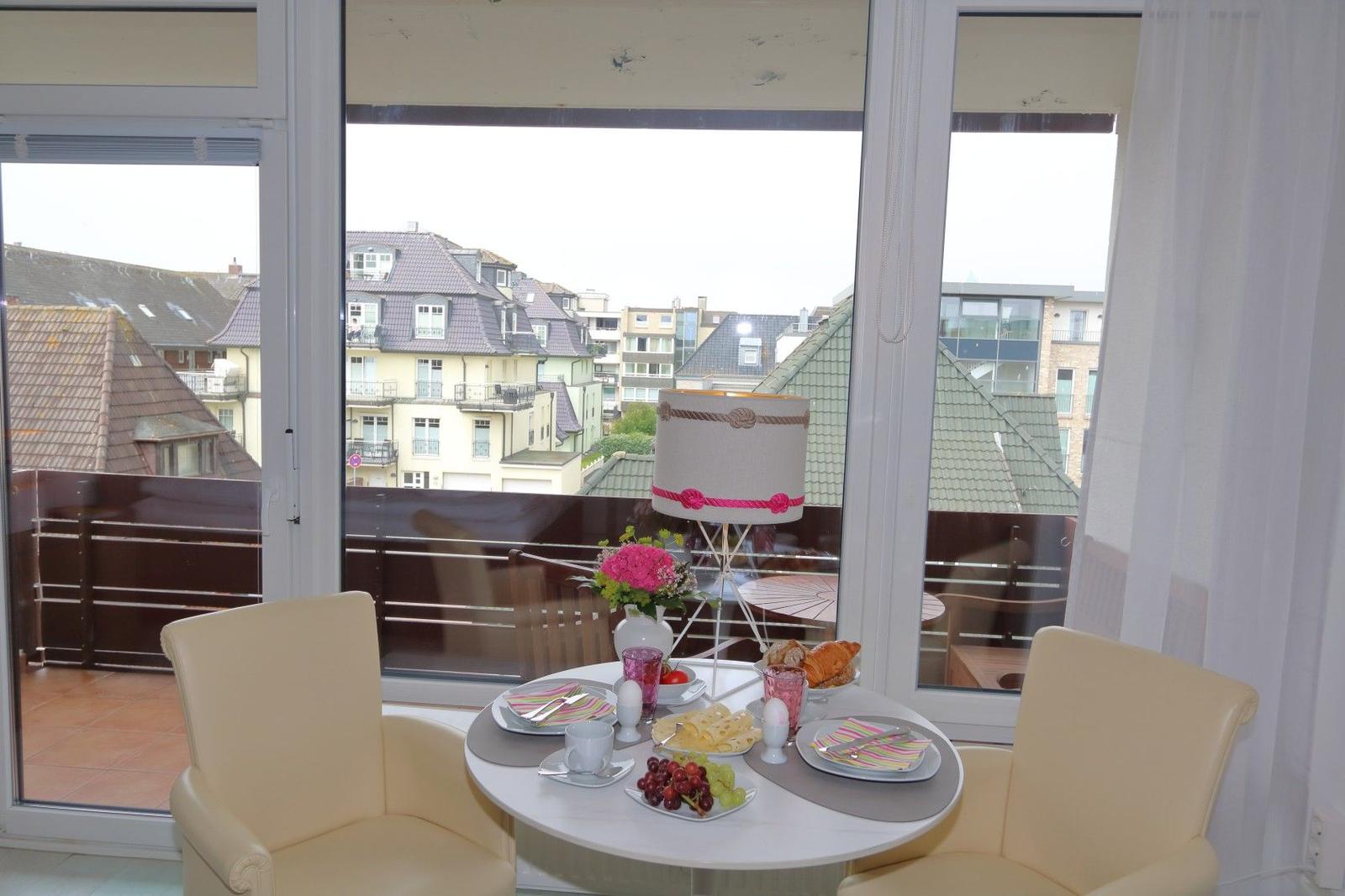 Rundes Tisch mit zwei Stühlen, Frühstück und Aussicht auf Dächer.