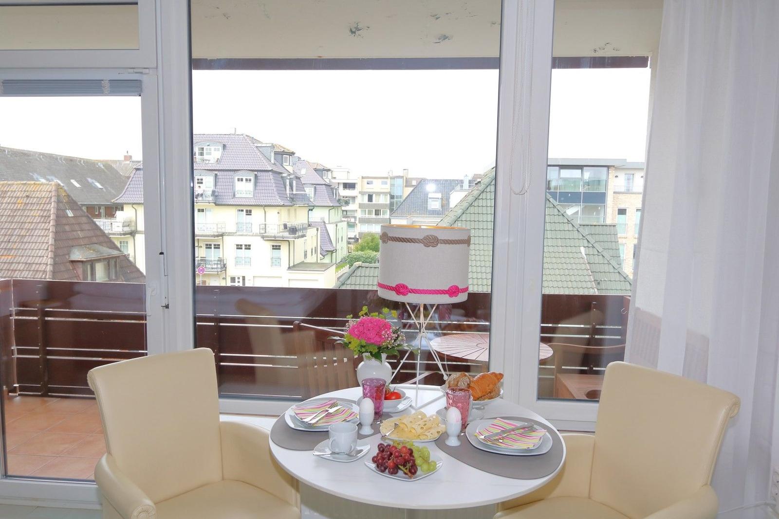 Rundtisch mit Stühlen vor Fenster mit Blick auf Dächer