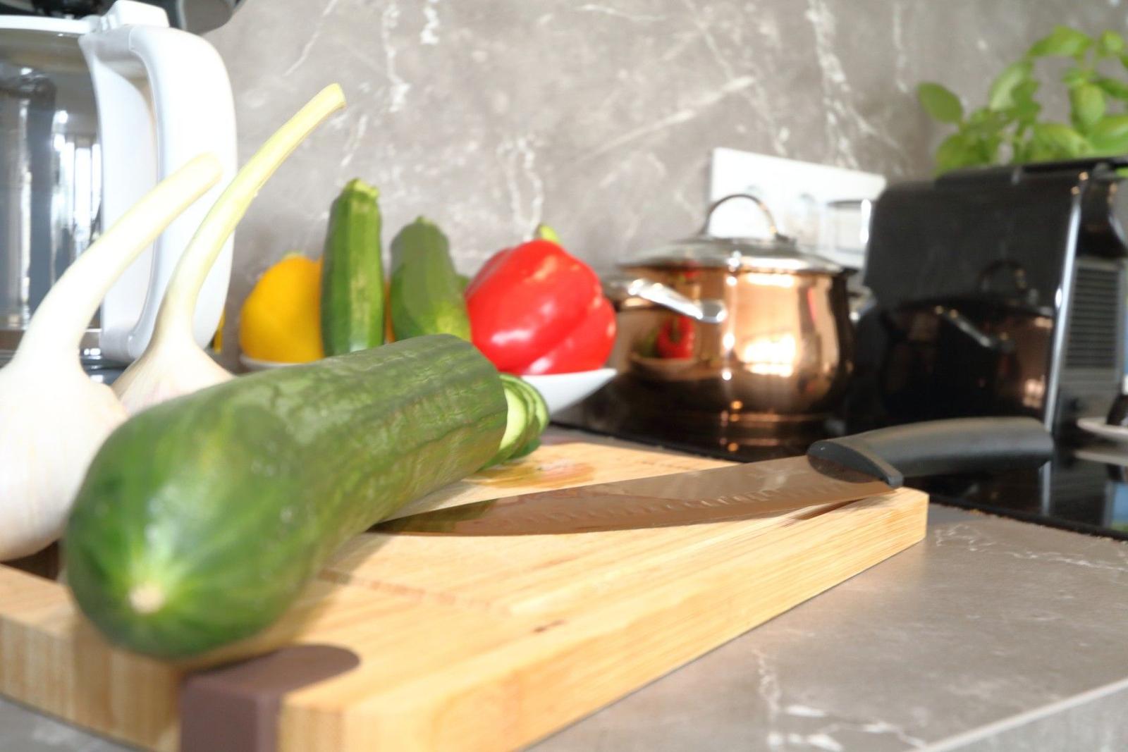 Küchenarbeitsfläche mit Zucchini, Gemüse und Küchenutensilien.