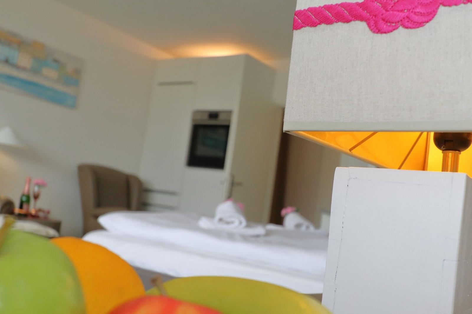 Schlafzimmer mit Bett, Lampe und Obst im Vordergrund