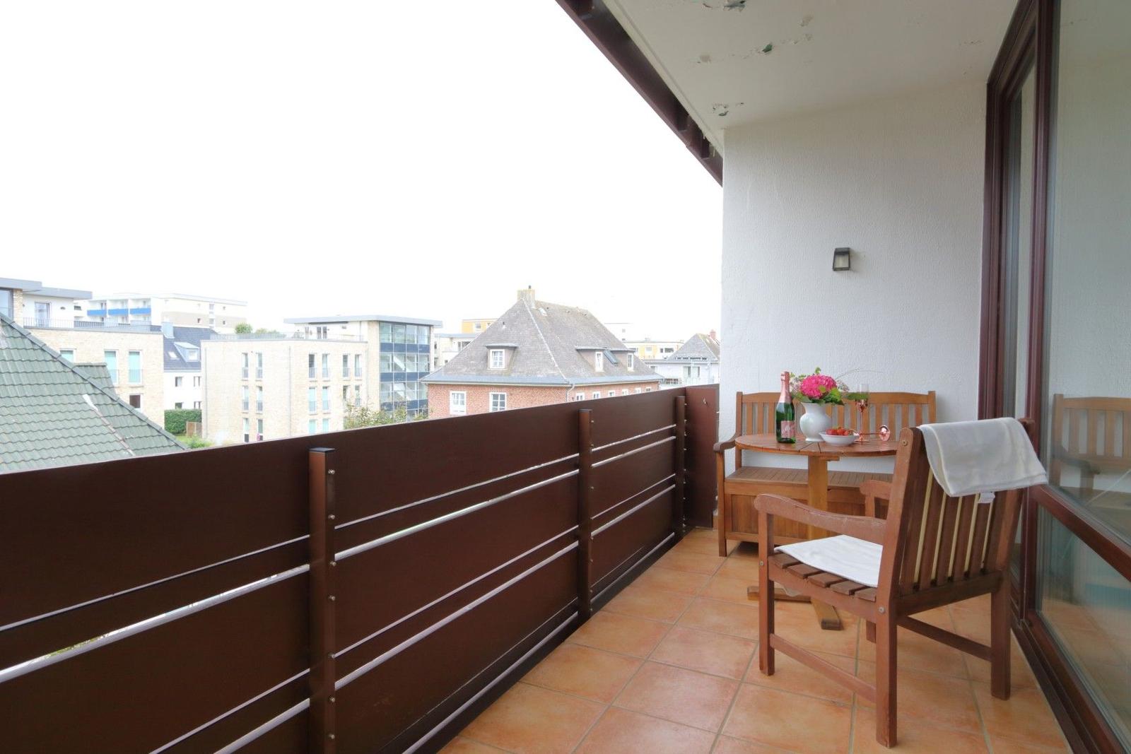 Terrasse mit Holztisch, Stühlen und Blick auf Wohngebäude.