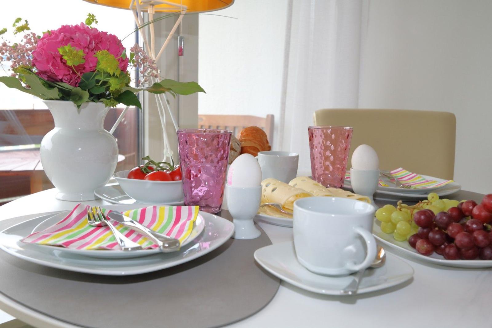 Frühstückstablett mit Obst, Eiern und Getränken. Blumenarrangement und Tischdekoration.