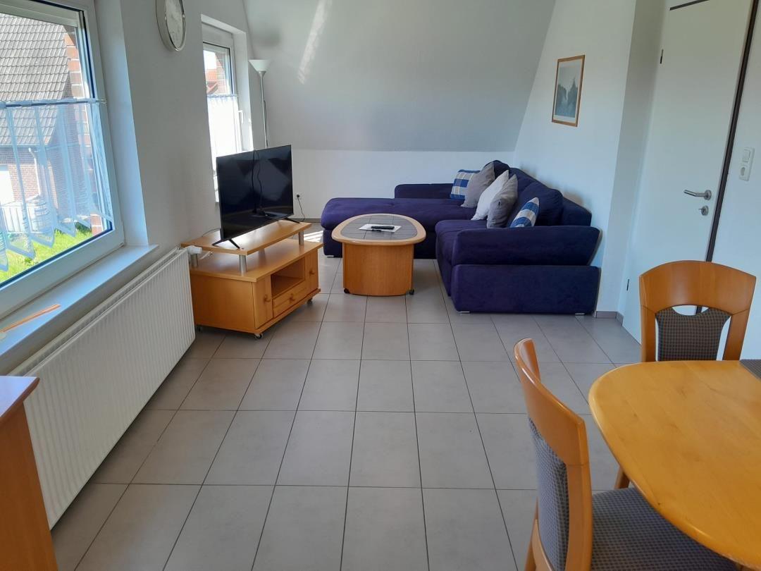 Wohnzimmer mit Sofa, Fernseher und Esstisch