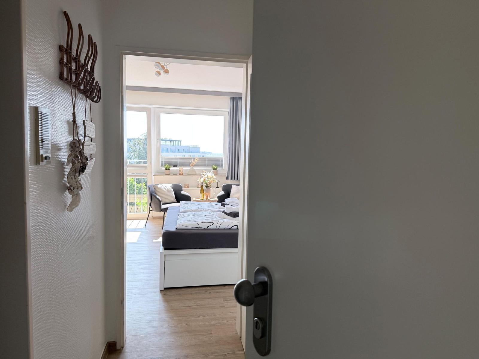 Durchgang in ein Schlafzimmer mit Bett und Balkon. Wand mit Haken und Dekoration.