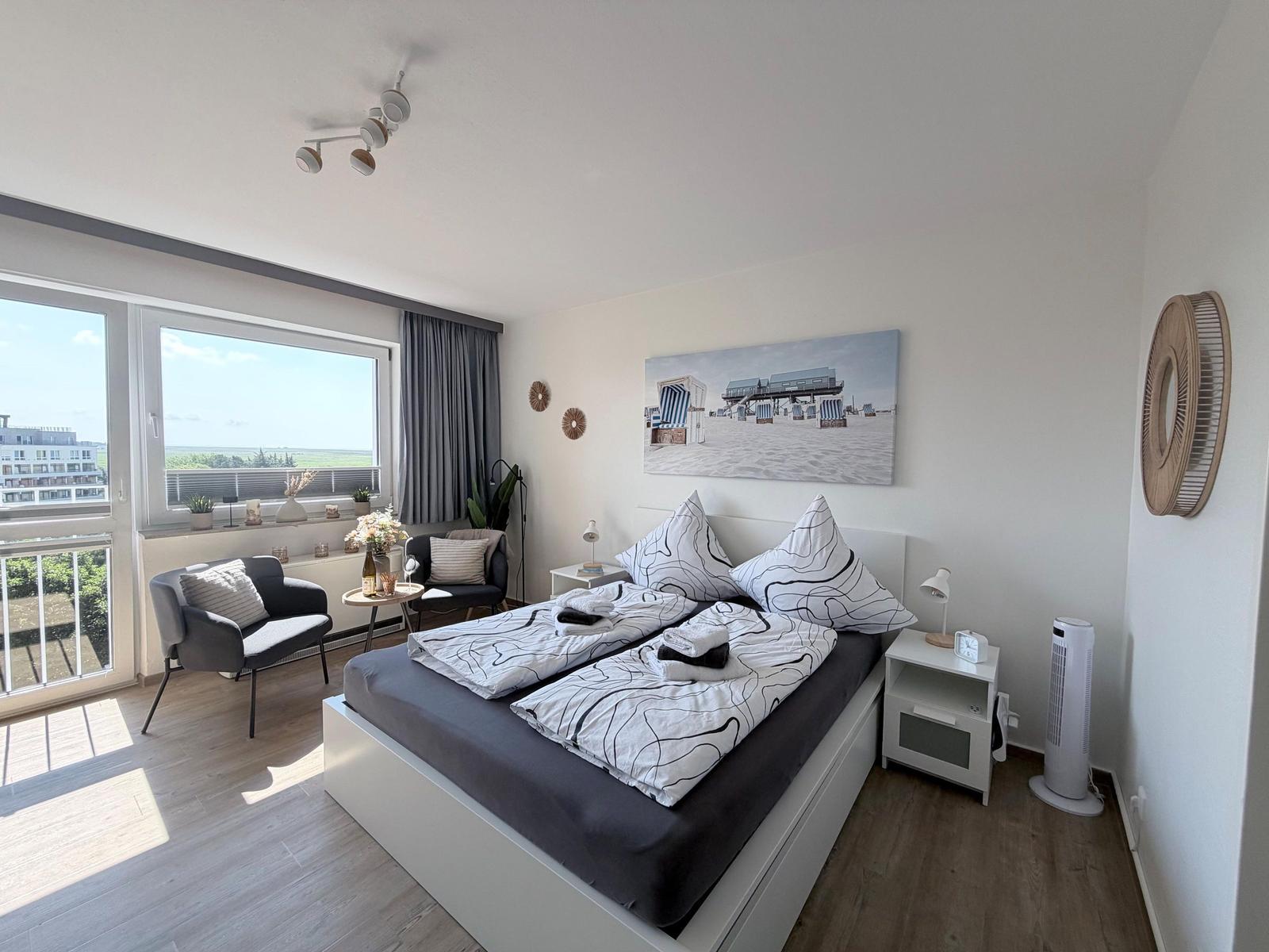 Schlafzimmer mit Doppelbett, Balkon und Wandbild. Zwei Nachttische und Stehlampe.