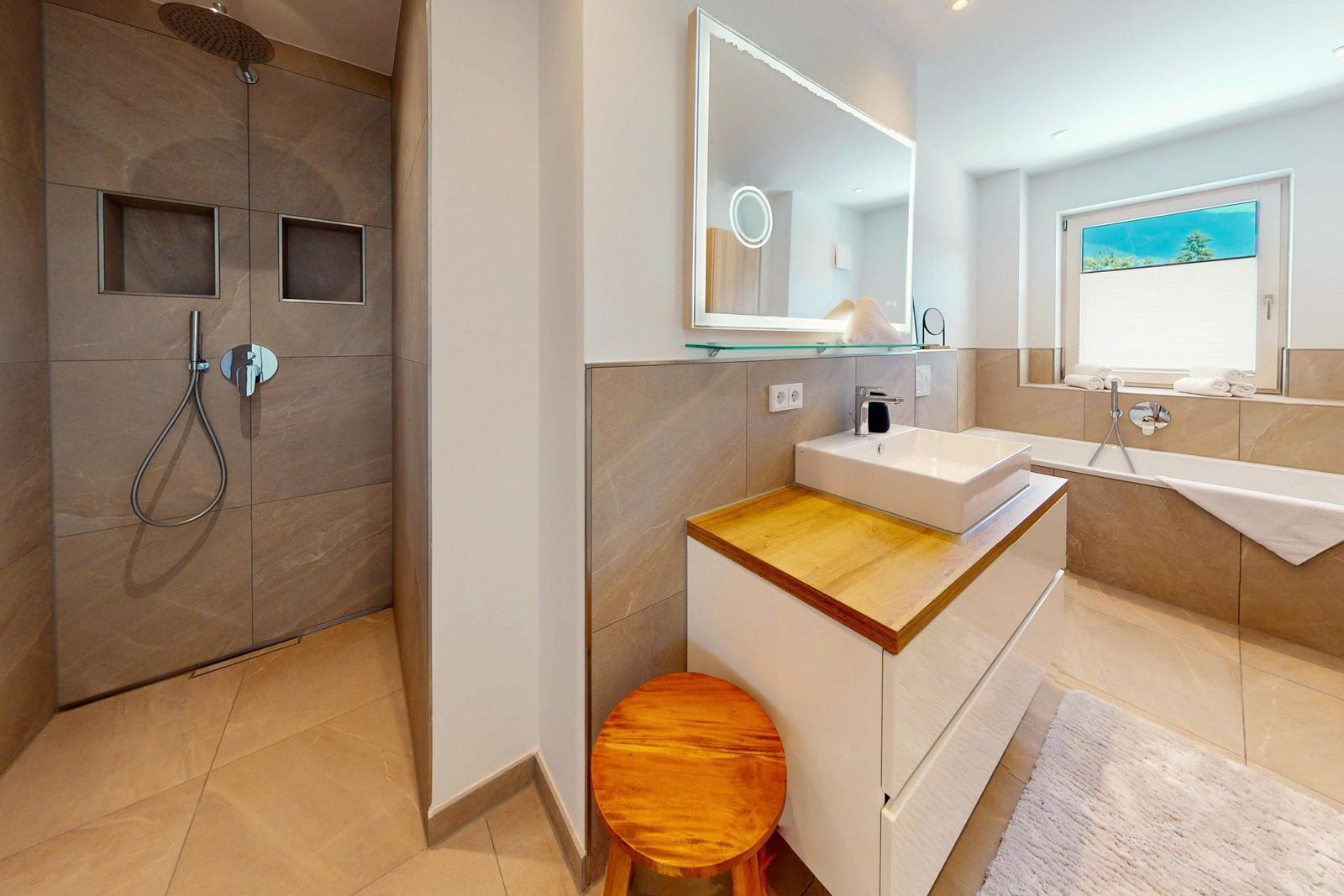 Bad mit Dusche, Waschbecken und Badewanne. Holzunterschrank und Spiegel.