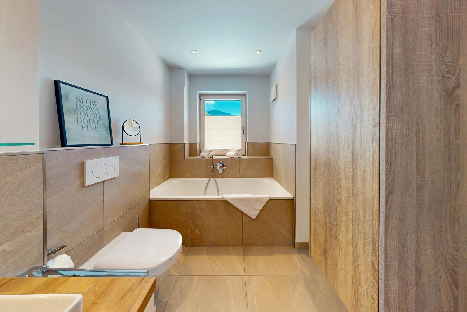 Badezimmer mit Badewanne, Fenster und Holzwand