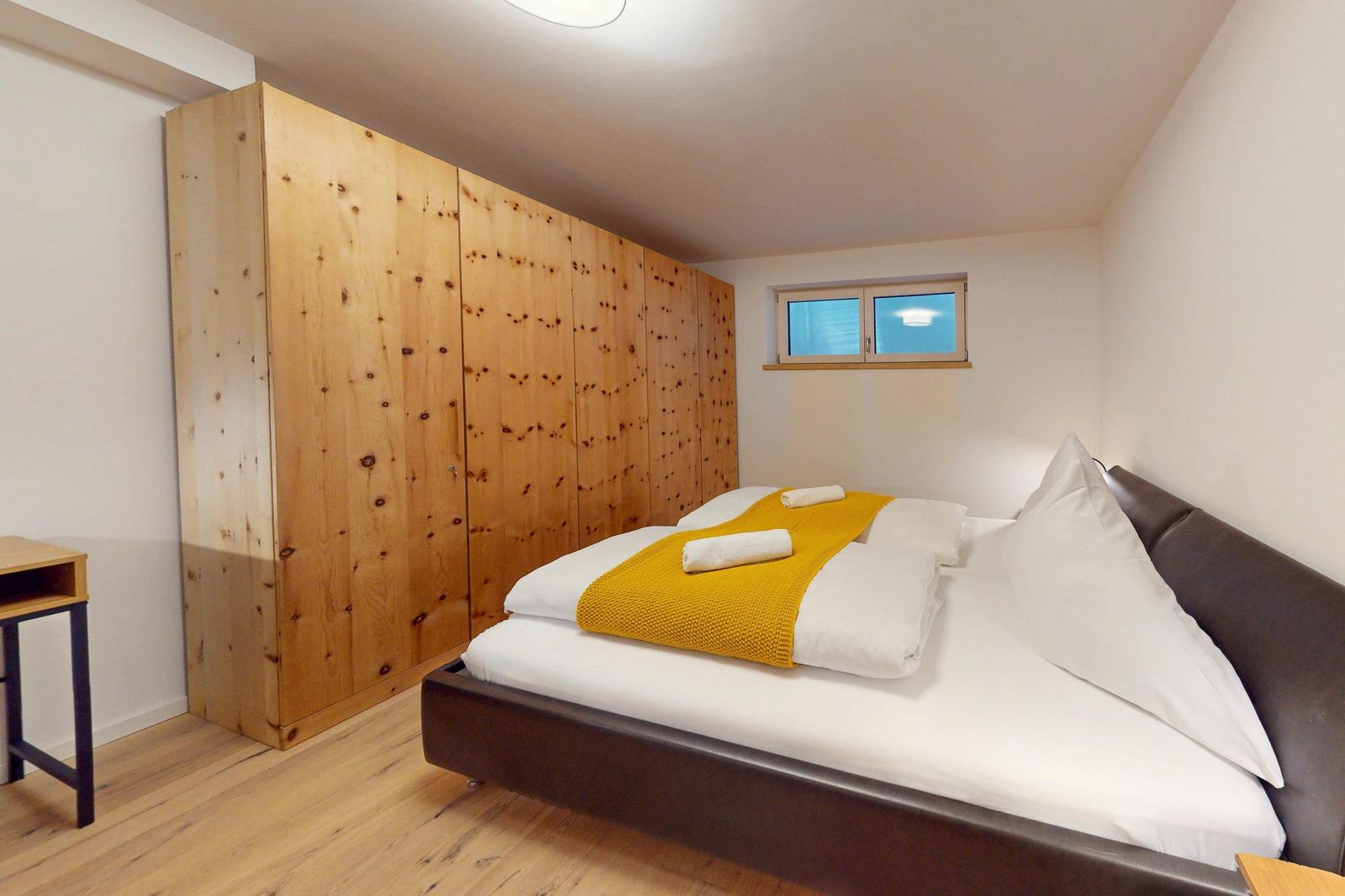 Schlafzimmer mit Holzwand, Bett und kleinem Fenster.