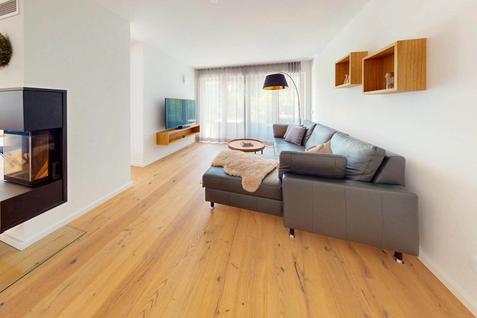 Wohnzimmer mit Sofa, Kamin und Fernseher an der Wand.