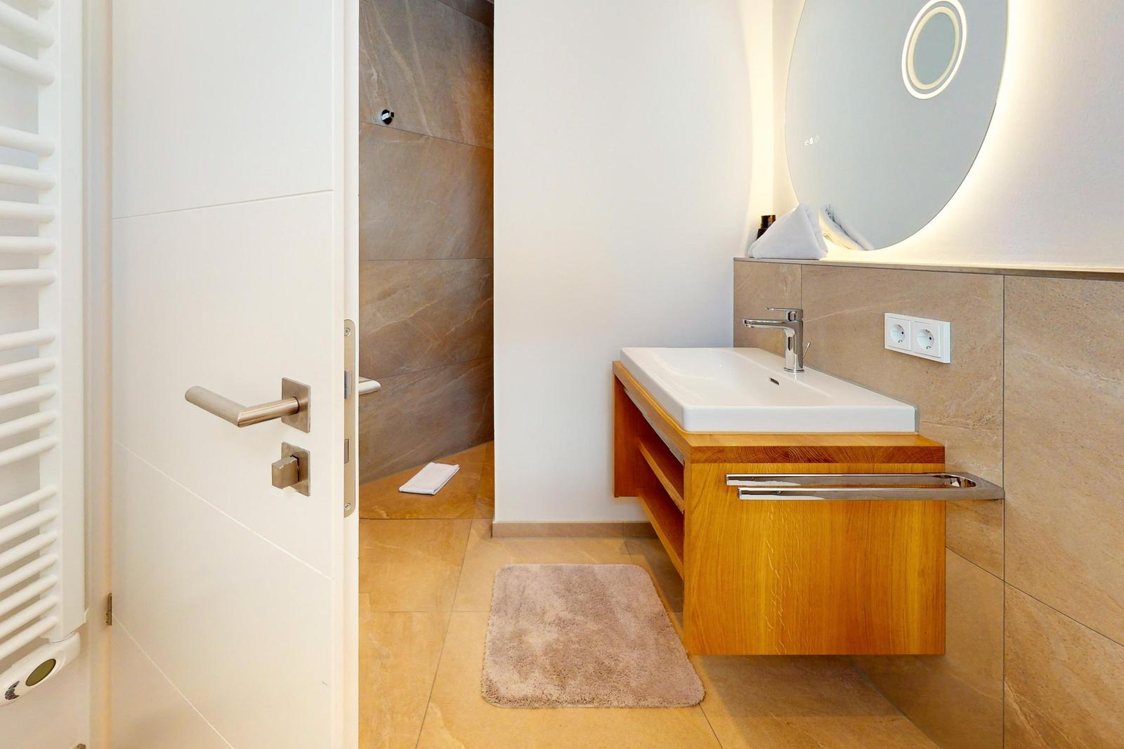 Badezimmer mit Waschtisch, Spiegel und Dusche.