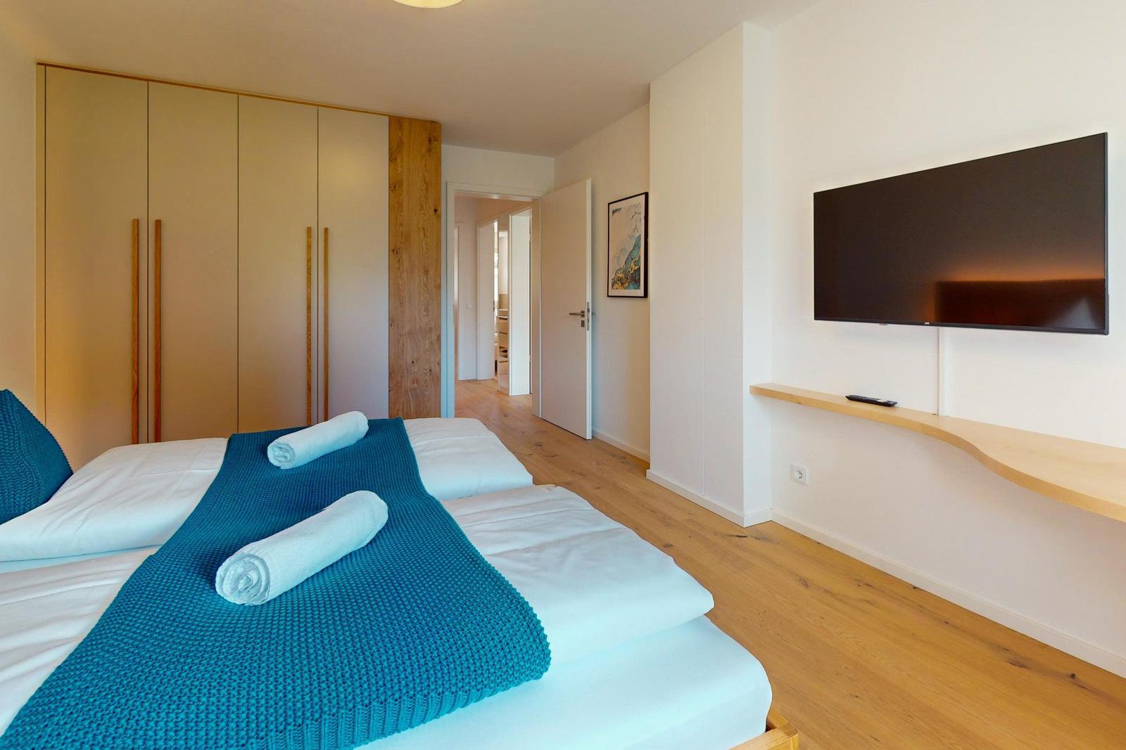 Schlafzimmer mit Doppelbett, Kleiderwand und Wandfernseher