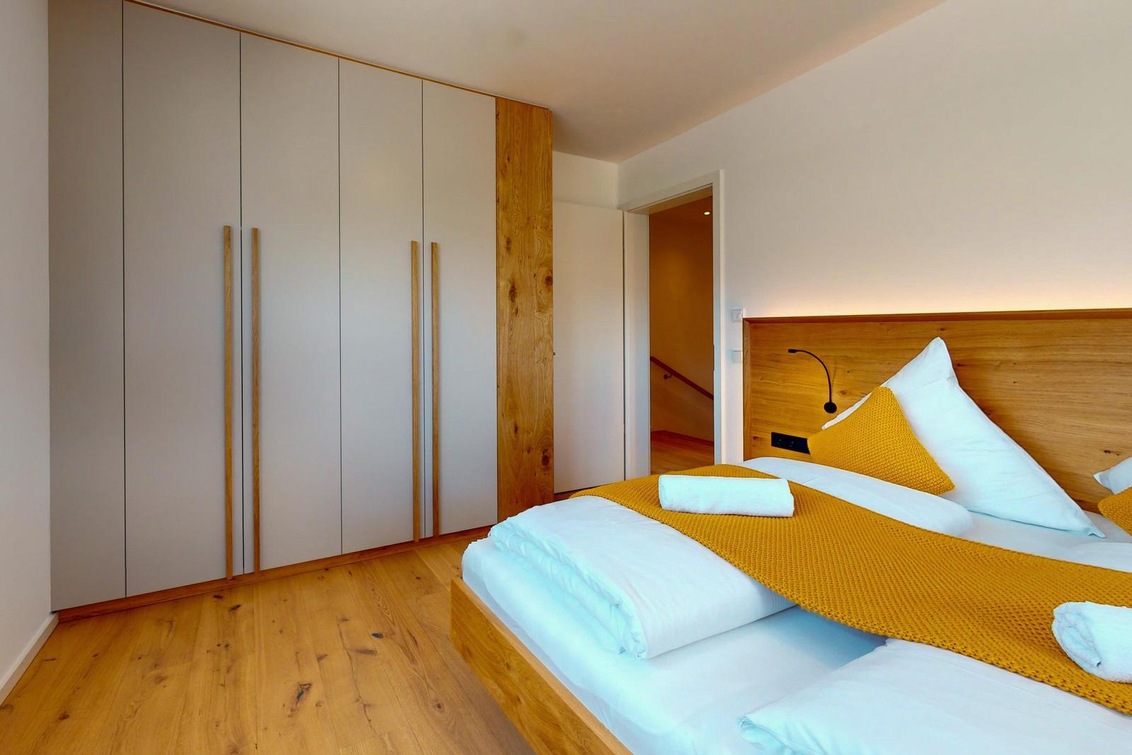 Schlafzimmer mit Bett, Kleiderschrank und Holzboden.