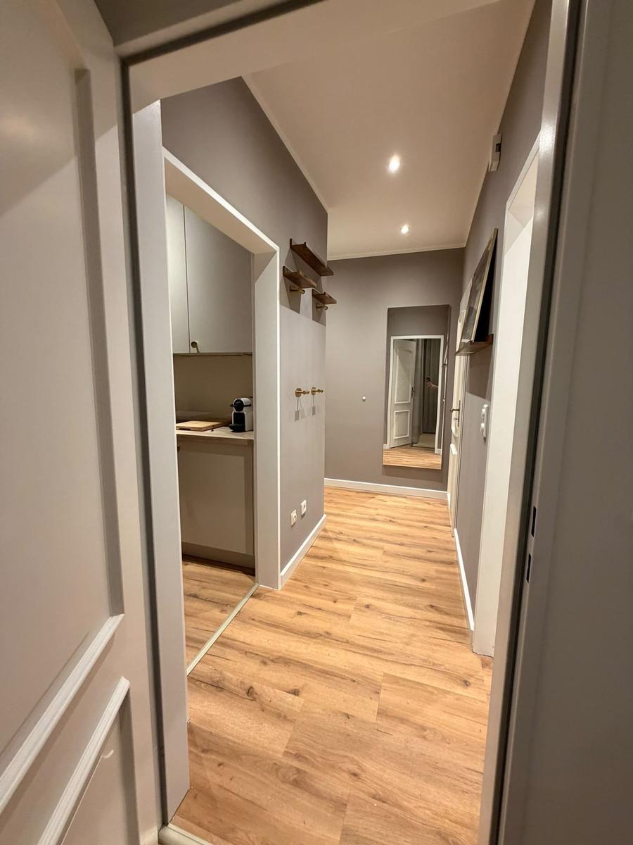 Flur mit Holzboden, Küchenbereich und Spiegel an der Wand.