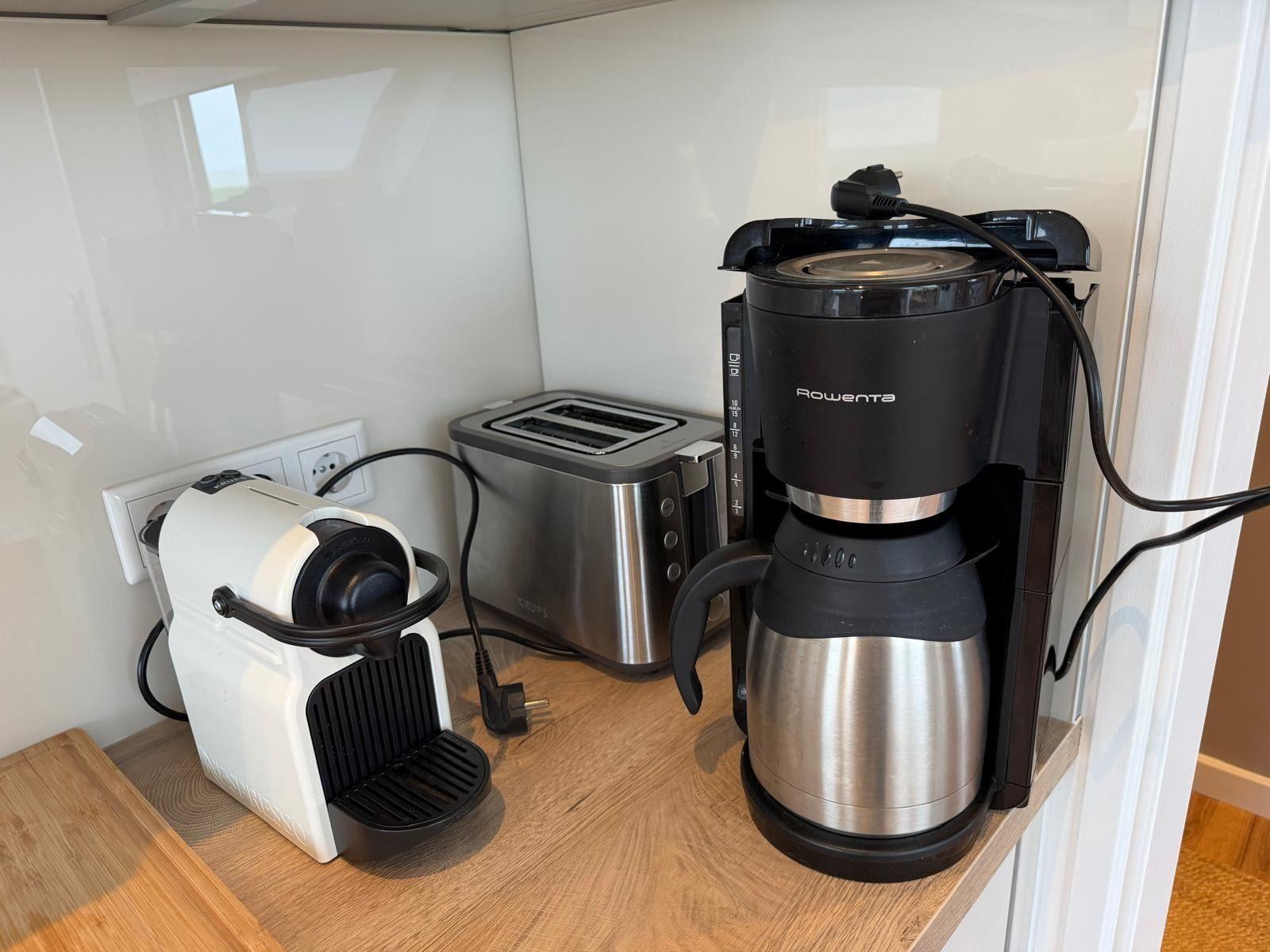 Küchenbereich mit Kaffeemaschine, Toaster und Kaffeekanne auf Holzoberfläche.