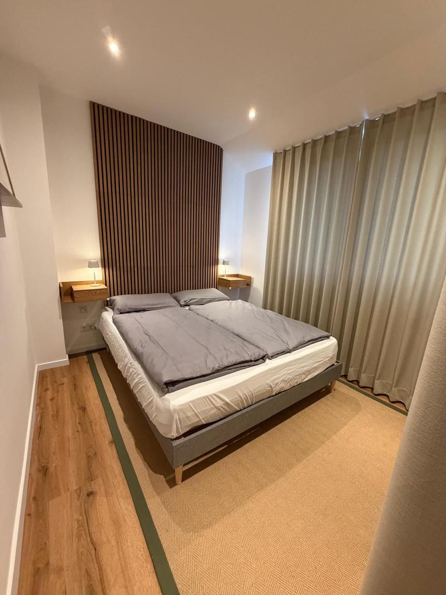Schlafzimmer mit Doppelbett, Holzboden und Holzpaneelen an der Wand.