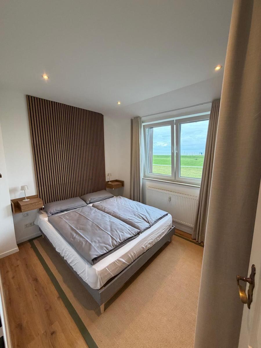 Schlafzimmer mit Doppelbett, Holzoberfläche und Fensterblick auf Grünland.