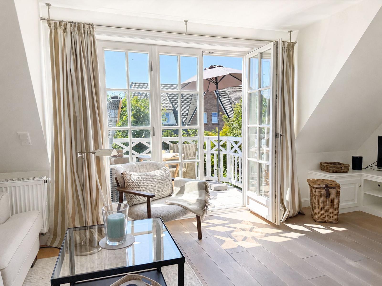 Wohnzimmer mit Balkon, Glas-Tisch, Sessel und Wickerkorb.