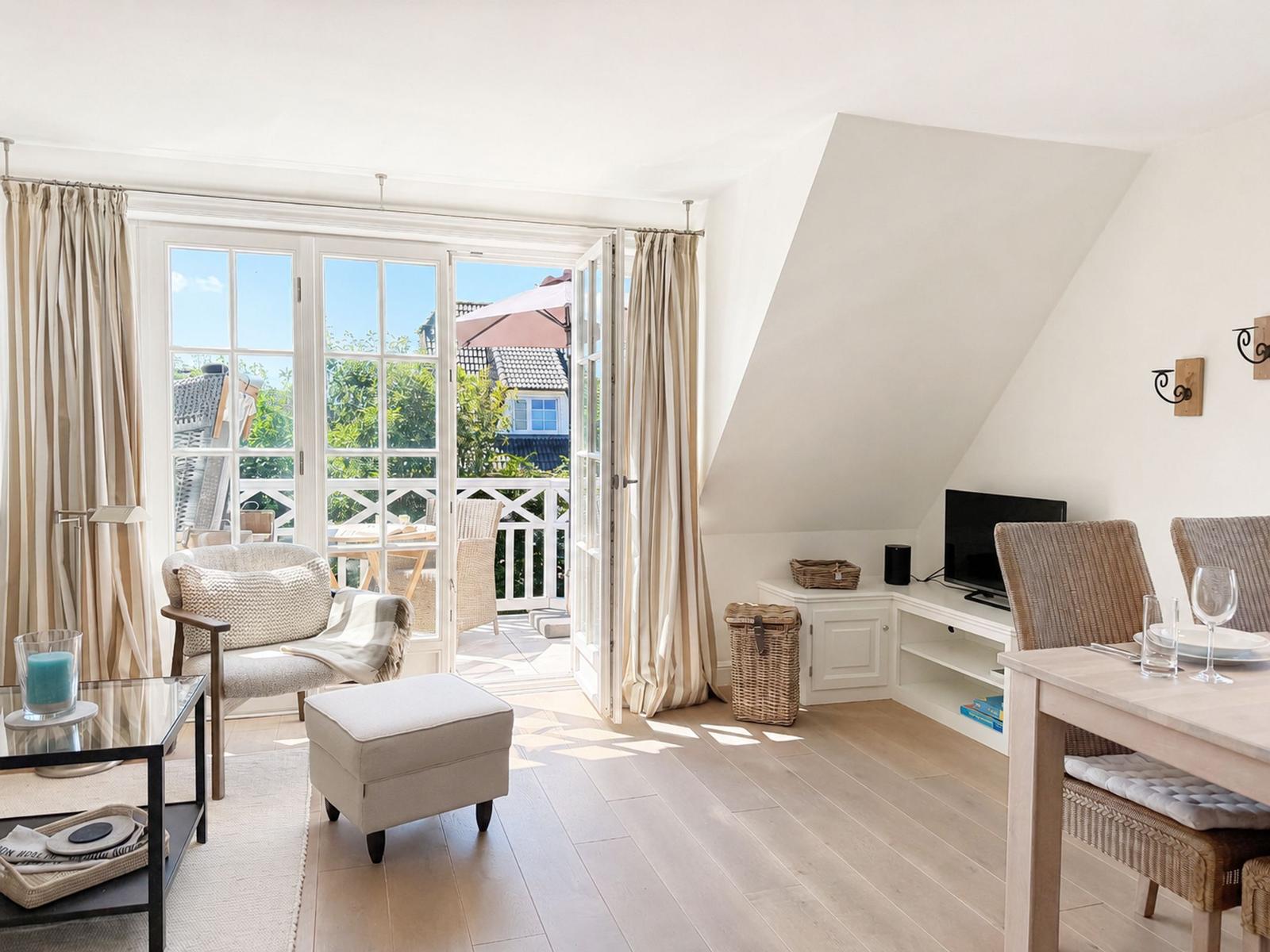Wohn- und Essbereich mit Balkon, Fernseher und Holzboden.